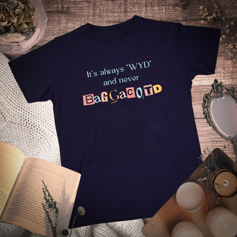 Op de afbeelding: Een marineblauw t-shirt met de tekst "It's always 'WYD' and never BagGaCoTD" gedrukt in kleurrijke letters.