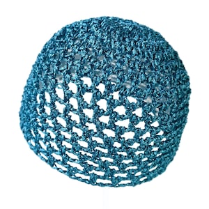 May include: A teal blue crocheted beanie hat. The hat is made of a loosely woven material, creating an open, airy design. The hat is a solid color and appears to be handmade. The hat is set against a white background.