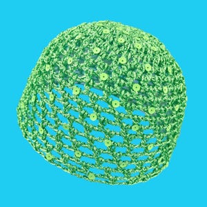 May include: A lime green crocheted hat with a net-like design and small, round sequins. The hat is made of a soft, textured yarn and has a rounded shape. The sequins are evenly spaced throughout the hat.