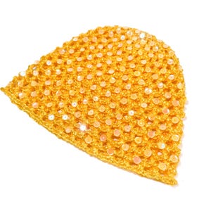 May include: A golden yellow crocheted hat with sparkling sequins. The hat is made of a textured yarn and is covered in small, round sequins that catch the light. The hat is a solid color and has a rounded shape.