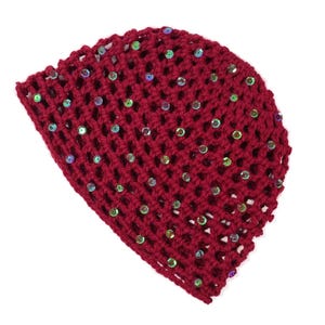 May include: A burgundy crocheted beanie hat with iridescent sequins scattered across the surface. The hat has a mesh-like design, allowing glimpses of the white background. This handmade hat is a stylish accessory.