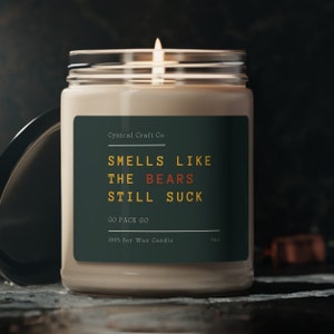 May include: A 9oz soy wax candle with a green label that reads "Cynical Craft Co. Smells Like The Bears Still Suck Go Pack Go".