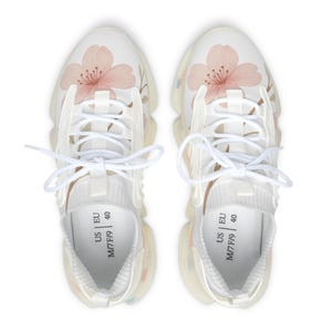 Könnte beinhalten: Paar weiße Sportschuhe mit floralem Design. Die Schuhe haben einen hellrosa Kirschblütendruck auf dem Zehenbereich. Sie haben weiße Schnürsenkel und eine transparente Sohle. Größe US M7/F9, EU 40.