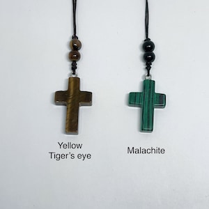 May include: Two necklaces with cross pendants. The cross on the left is made of yellow tiger's eye stone. The cross on the right is made of green malachite stone.