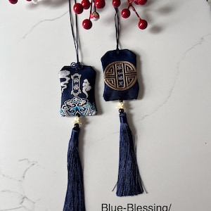May include: Two navy blue embroidered pouches with tassels, suspended by black cords. One has cloud and wave designs, the other a gold emblem. The text "Blue-Blessing/Harmony" is at the bottom.