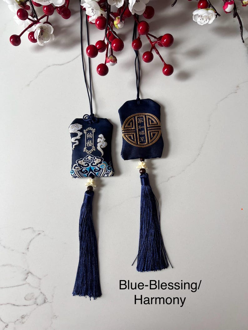 May include: Two navy blue embroidered pouches with tassels, suspended by black cords. One has cloud and wave designs, the other a gold emblem. The text "Blue-Blessing/Harmony" is at the bottom.