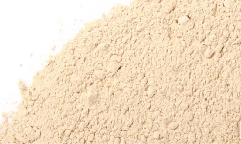 Puede incluir: Primer plano de un mont&oacute;n de polvo beige claro. El polvo es fino y suave, y tiene una textura ligeramente granulada.