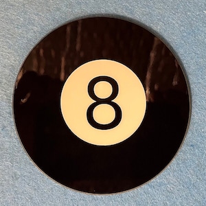 May include: A black and white 8-ball with a white number eight on a white background. The 8-ball is a classic pool ball.