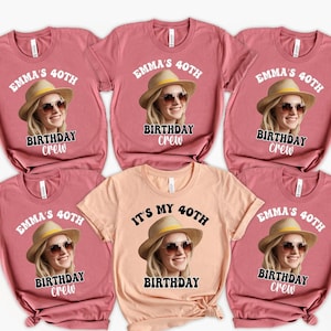 May include: A collection of short-sleeved t-shirts in shades of pink and peach. Each shirt features a graphic of a woman wearing a hat and sunglasses, with the text "EMMA'S 40TH BIRTHDAY CREW" or "IT'S MY 40TH BIRTHDAY".
