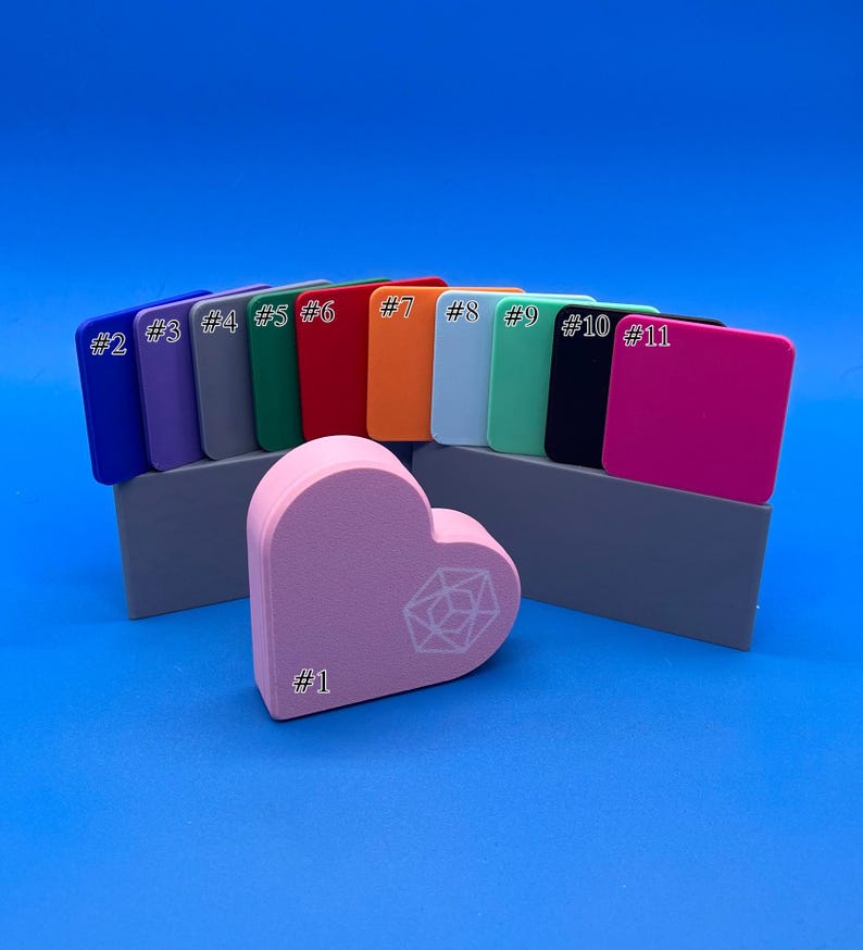 May include: A set of 11 colour swatches, numbered 1 through 11, with a pink heart-shaped object in the centre. The heart has a white geometric design and the text '#1' on it.