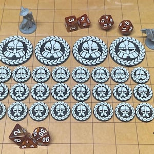 May include: A collection of tabletop gaming accessories, including dice and tokens. The dice are various shapes and colors, and the tokens feature a black and white design. Two miniature figures are also present, all arranged on a grid-patterned surface.