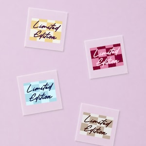 May include: Four square stickers with a light purple border, each featuring a checkered pattern in yellow, pink, blue, or tan. The text "Limited Edition" is printed in a dark script font across the center of each individual checkered square.