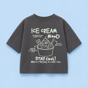 Könnte beinhalten: Ein anthrazitfarbenes Kurzarm-T-Shirt mit einer weißen Grafik eines Eisbechers und dem Text: ICE CREAM MOOD, ICE CREAM SOLVES EVERYTHING, SCOOP OF HAPPINESS, EVERY DAY IS BETTER WITH SPRINKLES ON TOP, STAY COOL!, BRAIN FREEZE IS LOADING...