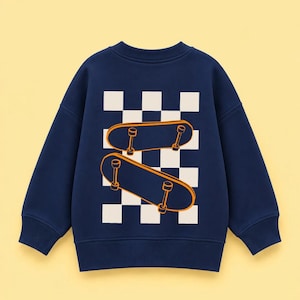 Könnte beinhalten: Ein langärmeliges Sweatshirt in Marineblau mit einer großen Grafik auf der Rückseite. Das Design besteht aus einem weiß-dunkelblauen Schachbrettmuster, das mit zwei orange umrandeten Skateboards in leichtem Winkel überlagert ist.