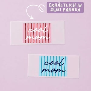 Può includere: Due etichette rettangolari con la scritta "cool mom" in corsivo. L'etichetta superiore ha uno sfondo rosa con strisce verticali rosso scuro, quella inferiore uno sfondo azzurro con strisce blu scuro. Un riquadro viola riporta "ERHÄLTLICH IN ZWEI FARBEN" con una freccia bianca.