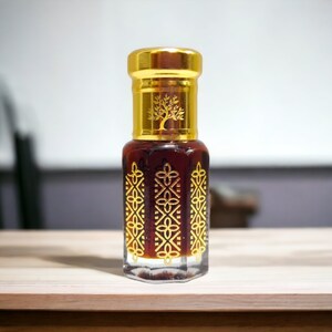 May include: A small, clear glass bottle with a gold cap and intricate gold designs. The bottle contains a dark brown liquid. The bottle has a tree logo on the cap.