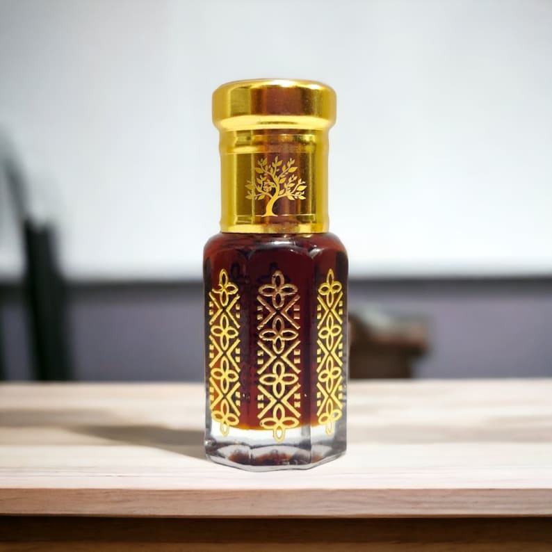 May include: A small, clear glass bottle with a gold cap and intricate gold designs. The bottle contains a dark brown liquid. The bottle has a tree logo on the cap.