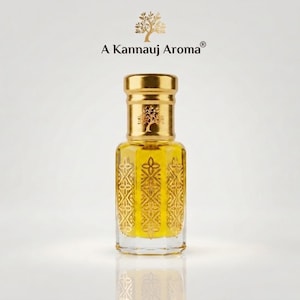 Pode incluir: Um frasco de perfume de vidro transparente com tampa dourada e líquido amarelo no interior. O frasco apresenta um padrão geométrico dourado intrincado nas laterais. Acima do frasco, o texto A Kannauj Aroma está impresso com um ícone de árvore.