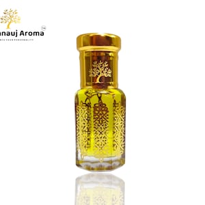 Puede incluir: Peque&ntilde;o frasco de perfume adornado con una tapa dorada y detalles dorados intrincados. El frasco contiene un l&iacute;quido amarillo y tiene una superficie reflectante. El logotipo "A Kannauj Aroma" es visible.
