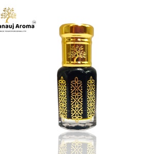 Op de afbeelding: Een klein, zwart glazen flesje met een gouden dop en ingewikkelde gouden ontwerpen. Het flesje is gevuld met een donkere vloeistof. Het flesje is gelabeld met "A Kannauj Aroma" met de tagline "Enhance Your Personality".