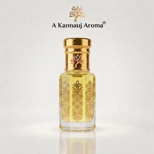 Può includere: Un flacone di profumo in vetro trasparente con un tappo dorato e un motivo geometrico color oro sui lati. Il flacone contiene un liquido giallo pallido. Sopra il flacone, il testo A Kannauj Aroma è stampato con una piccola icona di un albero.