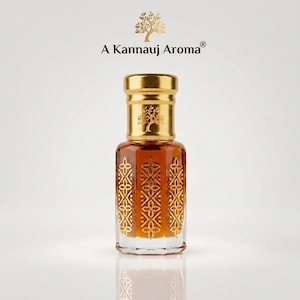 May include: A glass perfume bottle filled with amber liquid, featuring a gold cap with an embossed tree logo. The bottle has a hexagonal base with intricate gold floral patterns etched onto each side. Above the bottle, the text A Kannauj Aroma is displayed with a tree icon.