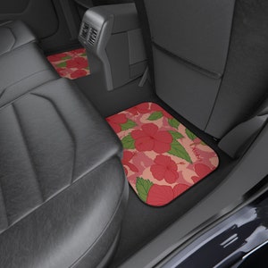 Op de afbeelding: Twee autovloermatten met een roze en groen hibiscus bloemenpatroon. De matten hebben het woord "Aloha" erop gedrukt.