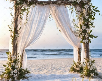 May include: A white fabric wedding arch decorated with white flowers and greenery, set up on a sandy beach with the ocean in the background.