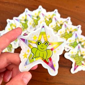 holographic Sticker "Queer Frog Star" Aufkleber – 6,5cm x 7cm – Wetterfest – süßer Charakter – Künstlerin Joca
