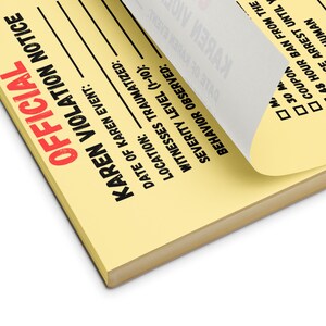 May include: A yellow notepad with the words "OFFICIAL KAREN VIOLATION NOTICE" in red and black. The notepad has lines for filling in details like the date, location, and severity level. A corner of the top page is lifted.