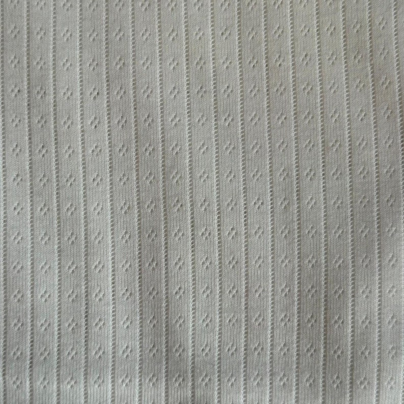 May include: White fabric with a textured pattern of vertical lines and small dots.