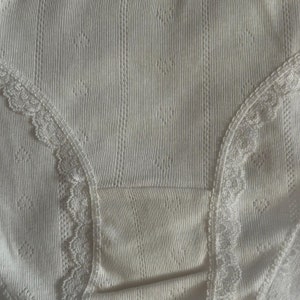 May include: White underwear with a lace trim. The underwear is made of a ribbed fabric and has a delicate, feminine design.