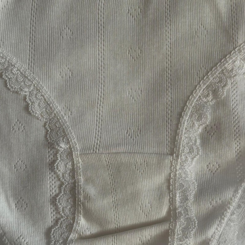 May include: White underwear with a lace trim. The underwear is made of a ribbed fabric and has a delicate, feminine design.