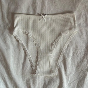 May include: White lace trimmed underwear with a ribbed texture.
