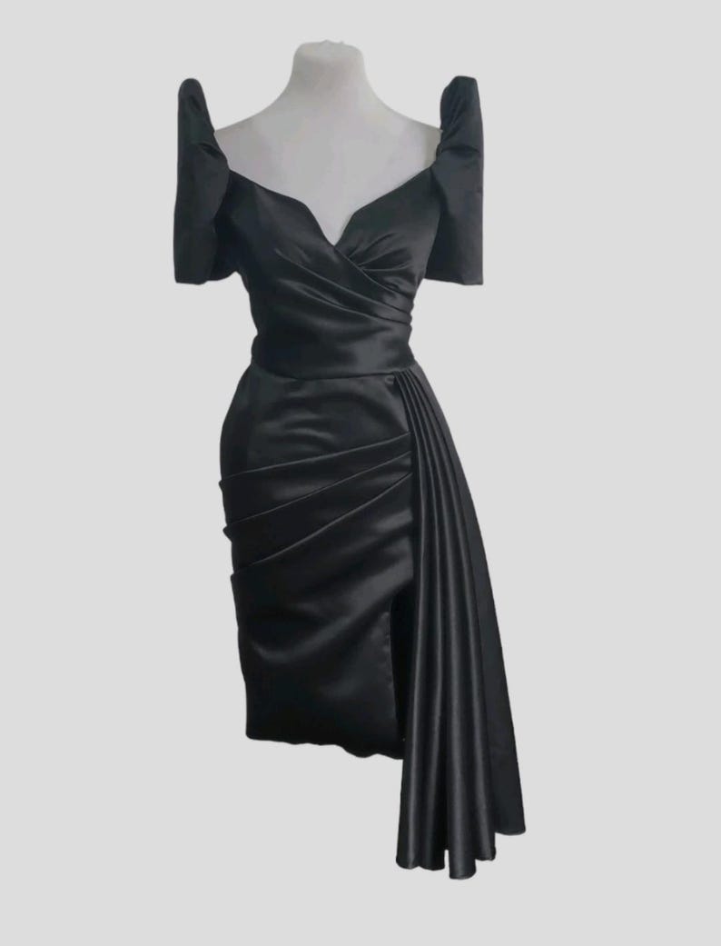 May include: A black satin dress with a sweetheart neckline and puff sleeves. The dress has a fitted bodice and a flowing skirt with a side slit.