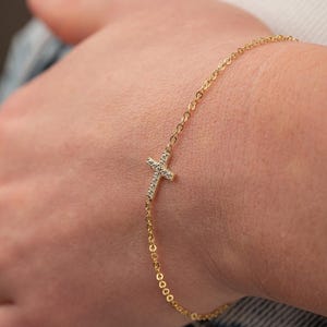 Peut inclure: Un bracelet en chaîne dorée avec un petit pendentif en forme de croix serti de diamants.