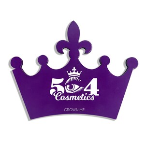 May include: Purple crown-shaped makeup palette with the text "524 Cosmetics" and "Crown Me" in white lettering.