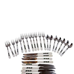 May include: A flatware set consisting of stainless steel forks, spoons, and knives. Each piece features a white handle decorated with a green holly leaf and red berry pattern. The set includes eight forks, six spoons, and eight knives.