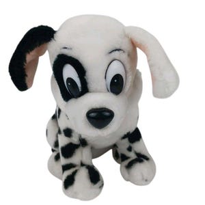 May include: A plush toy dog with white fur and black spots, featuring large white eyes with black pupils, a black nose, and one black ear. The stuffed animal is in a sitting position, showcasing a soft texture and a cartoon-like appearance.
