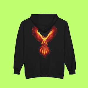 May include: Black hooded sweatshirt featuring a vibrant phoenix design on the back. The phoenix is depicted in shades of red, orange, and yellow, with outstretched wings and a fiery appearance. The sweatshirt has a drawstring hood and a kangaroo pocket.