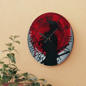Op de afbeelding: Een ronde wandklok met Romeinse cijfers en een zwart silhouet van een samoerai-krijger die een zwaard vasthoudt. De achtergrond is een rood en wit splatterpatroon.