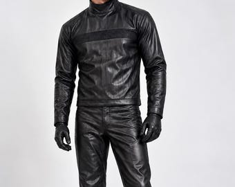 May include: A black leather outfit consisting of a long-sleeved mock neck top with a horizontal mesh panel across the chest, matching straight-leg trousers, and black leather gloves. The ensemble features vertical stitched detailing throughout.