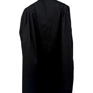 May include: A long, black robe with a high collar, displayed on a mannequin. The robe is made of a dark, opaque fabric and drapes down to the mannequin's feet. The mannequin's head is black and glossy, with a white collar visible.