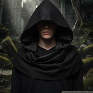 May include: A person wearing a black hooded cloak with a draped cowl. The cloak is made of a smooth, dark fabric. The background features an ancient stone structure and a sign that reads "GMG Costumes."