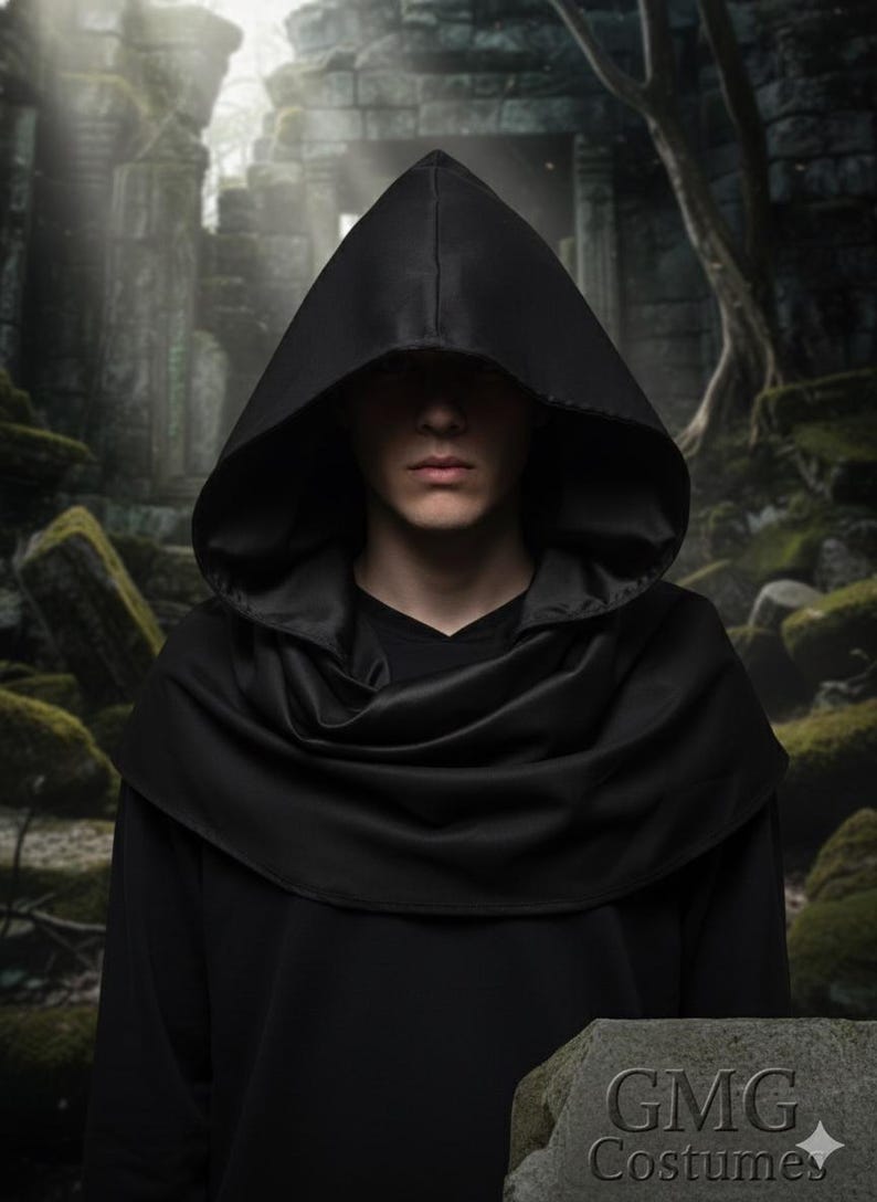 May include: A person wearing a black hooded cloak with a draped cowl. The cloak is made of a smooth, dark fabric. The background features an ancient stone structure and a sign that reads "GMG Costumes."