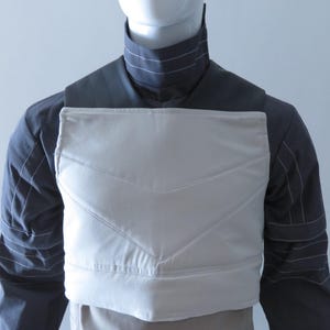 Puede incluir: Una taza de cer&aacute;mica blanca con un asa negra y el texto "But First, Coffee" en negrita negra. La taza se encuentra sobre un fondo borroso, sugiriendo un ambiente acogedor.