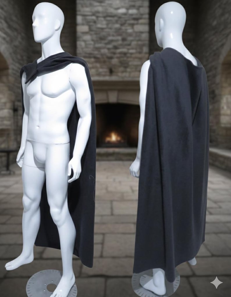 Puede incluir: Una capa gris oscuro drapeada sobre un maniqu&iacute;, mostrada de frente y de espaldas. La capa es larga, llegando a los tobillos del maniqu&iacute;. El fondo presenta una pared de piedra y una chimenea, lo que sugiere un tema medieval o de fantas&iacute;a.
