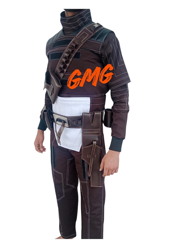 May include: Brown and white costume with a high collar, shoulder strap, and multiple pouches. The costume includes a belt, pants, and a holster. The text "GMG" is visible on the chest. The outfit has white stitching.