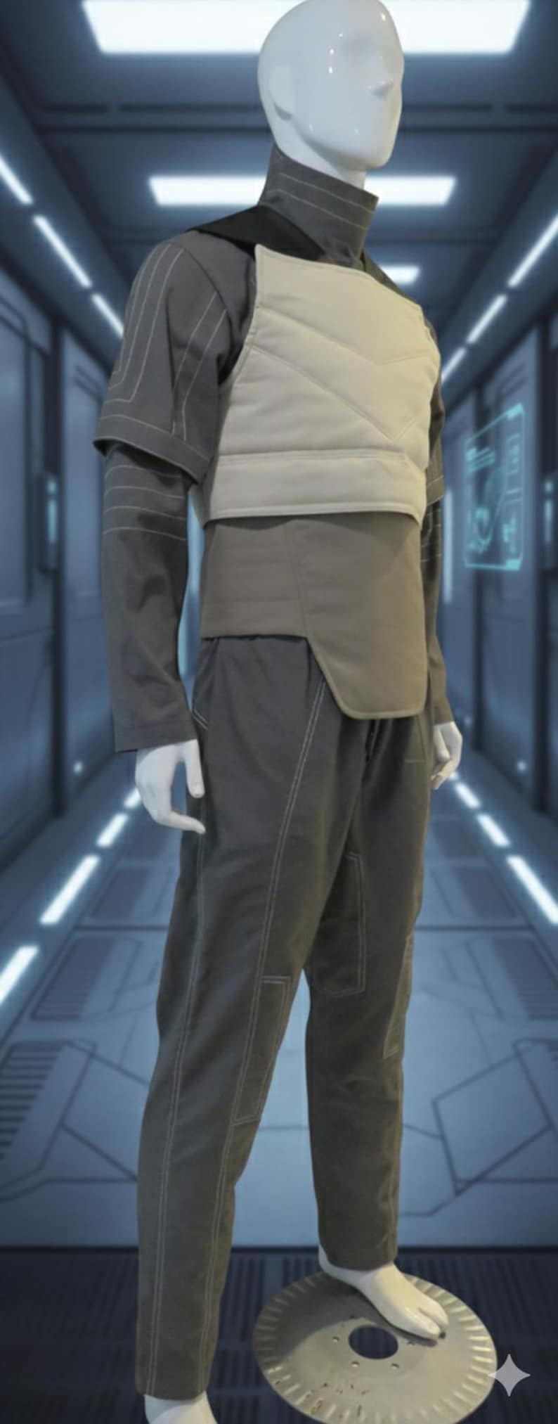 Puede incluir: Maniqu&iacute; con un atuendo gris futurista. El conjunto incluye una camisa de cuello alto, un chaleco acolchado, un cintur&oacute;n y pantalones a juego. Las costuras blancas acent&uacute;an las costuras. El atuendo se exhibe sobre una plataforma plateada.