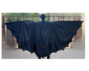 Op de afbeelding: Een zwarte cape met een breed, vleugelachtig silhouet met geschulpte randen die de vorm van vleermuisvleugels nabootsen. De stof is glad en donker en strekt zich horizontaal uit vanaf de schouders voor een brede, uitgestrekte spanwijdte.